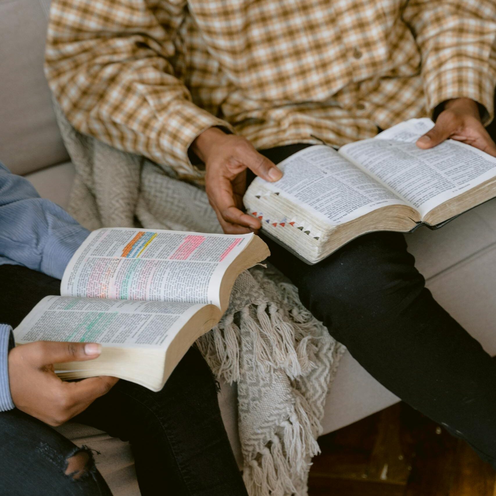 Two People Reading Bible while Sitting on a Sofa